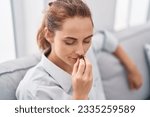 Young woman smelling marihuana bud sitting on sofa at home