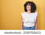 Young middle east woman standing over yellow background smiling looking to the side and staring away thinking. 