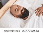 Young bald man lying on bed sleeping at bedroom