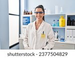 Small photo of Young beautiful hispanic woman scientist smiling confident standing at laboratory