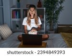 Young blonde woman sitting on the bed at home watching a movie from laptop skeptic and nervous, frowning upset because of problem. negative person. 
