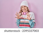 Small photo of Young blonde woman standing over pink background disgusted expression, displeased and fearful doing disgust face because aversion reaction. with hands raised