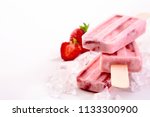 Three frozen popsicles with fresh strawberry ingredients stacked chilling on a bed of crushed ice with copy space alongside