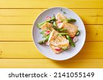 Small photo of Top view of palatable grilled tilapia fish with cut vegetables served on plate on wooden table