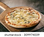 Flame grilled Italian Four Cheeses Pizza served steaming hot on a wooden board in a pizzeria or restaurant for a tasty savory fast food snack or takeaway, close up high angle view