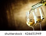 Pouring two glasses of white wine from a bottle in a close up view of the wineglasses over an abstract brown blue background with copy space