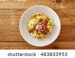 Plate of delicious spaghetti Bolognaise or Bolognese with savory minced beef and tomato sauce garnished with parmesan cheese and basil, overhead view