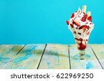Vanilla and strawberry ice cream sundae with flake on wooden table, blue background with copy space