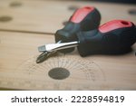 Flat screwdriver and Phillips screwdriver On woodworking workbench surface, small manual screwdriver, close-up