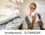 Energy efficient lighting choice: Pretty, young woman holding and choosing a LED diode light bulb for her lamp in DIY department store