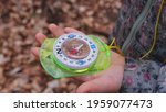 Small photo of Young Caucasian Girl Looking at Compass Magnetic Needle Settling Towards North during Orienteering Competition