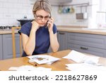 Small photo of A woman sits in the kitchen and talks on the phone, In front of the woman on the table are receipts, days, receipts from the store. Pretentious accounting. Communal payments for gas, electricity