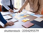 Small photo of A group of businesspeople gather around a meeting desk engrossed in a conference, discuss strategies, growth plans, and the company's vision as they jot down goals on post-it papers, layingthe foundat
