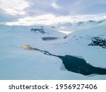 Stunning aerial view of a river flowing through a snow covered tundra and mountain range.