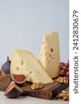 Small photo of Maasdam cheese with walnuts and figs. Two pieces of maasdam cheese on a wooden board.