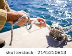 Small photo of strong hands pulling hard on some ropes and moorings of a ship at the dock