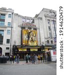 Small photo of LONDON - ENGLAND - JULY 11, 2012: People wait at the traffic light in front of the Dominion Theatre at Tottenhan Court Road in London.