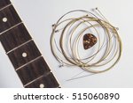 Acoustic guitar strings, pick and guitar neck on gray paper background