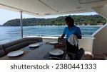 Small photo of Phuket, Thailand, 30,September, 2023: A stewardess on a private yacht lays out cutlery on the table in the cockpit, a stewardess on a yacht lays out cutlery before dinner
