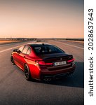 Small photo of Kharkiv, Ukraine - July 2021: BMW M5 F90 finished in Motegi Red color at sunset