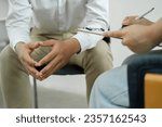 Small photo of Psychiatrist or counselor holding the patient's hand to comfort and encourage. Young Asian female psychologist keeping hand of wrist of male patient sitting in front of her and sharing his problems.