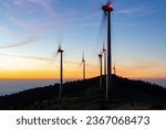 Group of windmills for electric power production on a mountain ridge short before sunrise