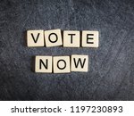 Letter tiles on black slate background spelling Vote Now