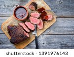 Barbecue dry aged wagyu tri tip steak with BBQ sauce as dip as top view on a wooden cutting board with copy space 