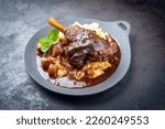 Modern style traditional braised slow cooked lamb shank in red wine sauce with shallots and mashed potatoes offered as top view in a design cast iron plate with copy space 