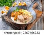 Small photo of Modern style traditional barbecue pork filet medaillons in cream sauce with chanterelle mushrooms and spaetzle offered as close-up on a rustic wrought iron skillet