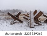 Small photo of empty roadblock on the road. concrete slabs, sandbags and anti-tank hedgehogs restrict traffic. military structures on a winter road. blizzard and ice on the road at the patrol post. war in ukraine