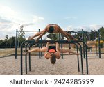 Small photo of couple training together in a calisthenics park. doing back lever and straddle planche.