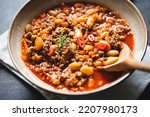 Small photo of Chili Con Carne in bowl on dark background. Mexican cuisine. chili con carne - minced meat and vegetables stew in tomato sauce. Top view