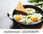 Small photo of green shakshuka in a cast iron skillet. fried eggs with spinach and fried toast. healthy nutritious breakfast