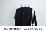 3 Black Suits Hung On A White...