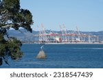 Small photo of Tauranga New Zealand - June 6 2023; Statue of Tangaroa mythical god of sea in entrance to Tauranga Harbour with port container cranes in background