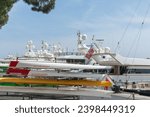 Small photo of Monaco May 2 2011; luxury boats moored beyond rowing skiffs on rack on wharf