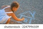 Small photo of Child draws house with colored chalk on pavement in park. Children drawing with colored chalk on pavement. Drawing of house on road. Children dream with chalk. Child draws with chalk