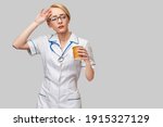 Portrait of a female doctor holding paper cup of coffee standing over grey background