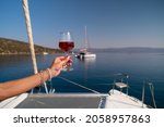 Female hand holding glass of wine on sea background
