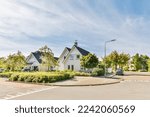 Small photo of a street with houses and cars parked in the parking lot on either side of the road there is a blue sky filled with white