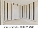 an empty room with black and white striped wallpapers on the walls there is a door in the corner