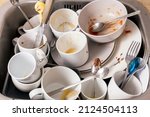 Small photo of Pile of unwashed, dirty dishes in the sink. Mess in the kitchen. Dirty kitchenware, plates and mugs. Chaos at home. Laziness. Cluttered apartment. Messy cutlery and dishware.