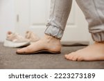 Small photo of Flat feet diagnosis and orthotics, shoe inserts. Problems with flatfoot, pain. Identification of flat foot. Treatment to plantar fasciitis. Womans foot and insoles at home, close up view.