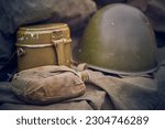 Military flask in a case with a military helmet and mess kit in blur. Close up WW2 army ammunition. The concept of victory and memory of the fallen soldiers.
