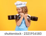 Small photo of Kid chef cook with cooking pot stockpot. Cooking children. Chef kid boy making healthy food. Portrait of little child in chef hat isolated on studio background. Kid chef. Cooking process.