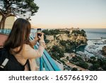 Fascinating lady standing at viewpoint and take photo Principality of Monaco, sightseeing the stunning skyline of sea and panorama Monaco.