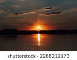 A sunset over a lake with a cloudy sky