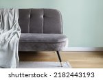 Web banner view of comfortable grey suede couch with soft plaid in living room. Sofa against green copy space wall in cozy apartment with wooden parquet floor