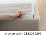 Small photo of Cropped view of woman hand is holding zipper or opened fastener, changing protective cover on the mattress. Waterproof bedding on bed in bedroom. Laundry and dry cleaning concept